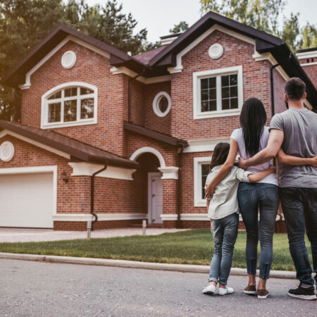 Eine Familie steht vor einem großen Backsteinhaus und betrachtet ihr neues Zuhause, symbolisiert durch die Immobilienverwaltung M&S aus Datteln.