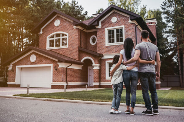 Eine Familie steht vor einem großen Backsteinhaus und betrachtet ihr neues Zuhause, symbolisiert durch die Immobilienverwaltung M&S aus Datteln.